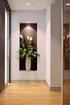 a vase filled with flowers sitting on top of a wooden floor next to a wall