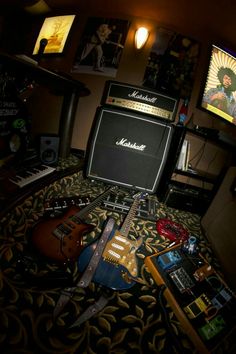 guitars and amps are sitting on the floor in front of two televisions,