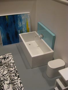 a bathroom with a sink, toilet and painting on the wall