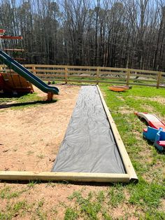 there is a slide in the middle of an empty play area with plastic tarps