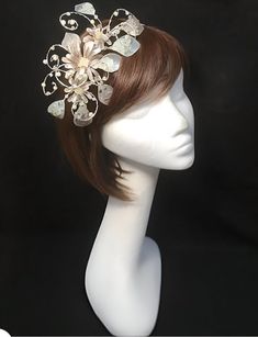 Delicate silver beige fascinator perfect for the guest who wants something fairly understated.  This design is a beautiful selection of glass effect leaves and flowers clustered together and set onto a fine comfort base tiara band. As with all our designs, this piece can be made exact to the image or in any colour combination to match in with your outfit. If a specific colour is required customers can message over an image of their outfit and accessories, or if time allows customers are always w Beige Mini Hat Headband For Weddings, Elegant Cream Headband Costume, Elegant Beige Wedding Headpieces, Beige Hair Accessories For Wedding, Cream Pinched Crown Fascinator For Party, Cream Headpiece With Pinched Crown For Evening, Elegant Cream Headband For Party, Beige Wedding Headband, Cream Bridal Accessories For Mother Of The Bride