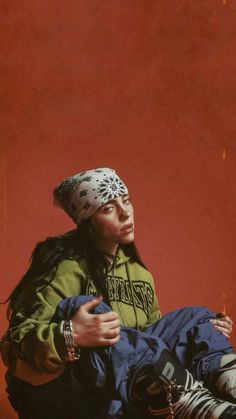 a woman sitting on the ground with her head wrapped in a bandana and looking at something