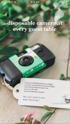 a green and black camera sitting on top of a table next to a tag with the words disposable camera at every guest table