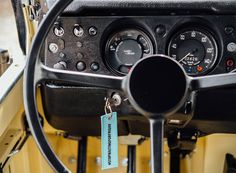 the steering wheel and dashboard of an old car with a tag hanging from it's center console