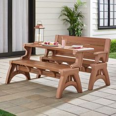 a wooden bench sitting on top of a patio next to a table with two chairs