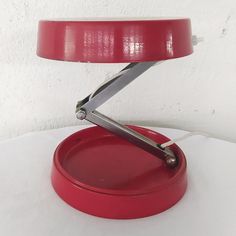 a red table lamp sitting on top of a white table