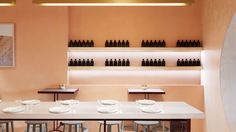 a dining room table with white plates and wine bottles on the wall