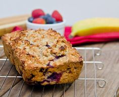 a muffin sitting on top of a cooling rack next to some bananas and strawberries