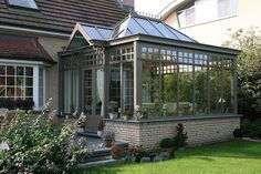 a house that has some plants in front of it and flowers on the ground outside