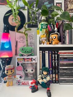 a shelf filled with books and toys next to a plant on top of a table