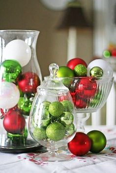 christmas decorations in glass vases sitting on a table next to other ornaments and decor