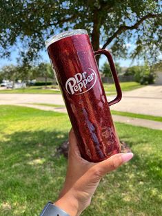 a person holding up a red cup in their hand with the words dr pepper on it