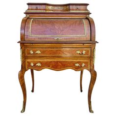 an old fashioned wooden desk with drawers and gold trimmings on the top, against a white background