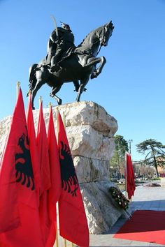 a statue of a man on a horse with two flags in front of him and another one behind it