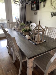 a dining room table with white chairs and a wooden centerpiece on top of it