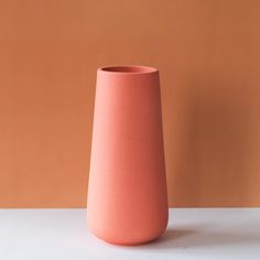 a pink vase sitting on top of a white table