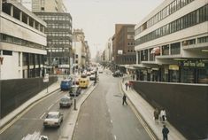 a city street filled with lots of traffic and people walking on the side of it