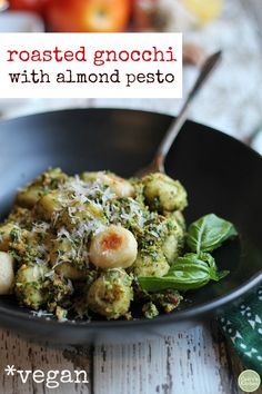 a black bowl filled with pasta and broccoli on top of a wooden table