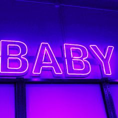 a neon sign that says baby on the side of a building with purple light behind it