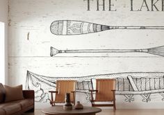 two chairs and a table in front of a wall with canoes painted on it