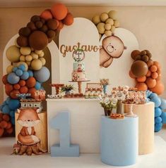 a birthday party with balloons and decorations on the wall, including an animal themed cake table