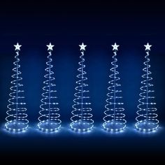 five christmas trees with lights on them in the shape of stars, against a dark background