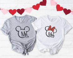 two t - shirts with mickey and minnie mouse heads on them, one is grey and the other is white