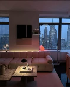 a living room filled with furniture and tall buildings in the background at night time,