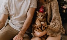 a man and woman sitting next to each other holding a cat