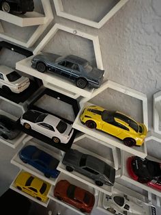 toy cars are lined up on shelves in a room with white walls and ceiling tiles