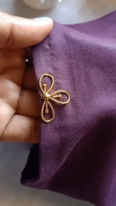 a person holding onto a purple cloth with a gold bow brooch on it's side