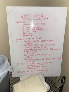 a white board with writing on it next to a trash can and some other items