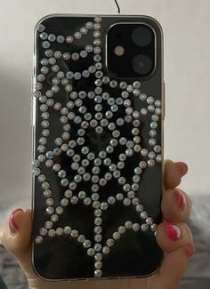 a woman holding up her phone case with diamonds on it