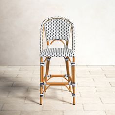 a wicker bar stool with black and white stripes on the seat, in front of a wall