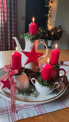 a tea set with candles and decorations on a table in front of a christmas tree