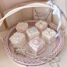 a basket filled with pink and white cakes on top of a table next to scissors