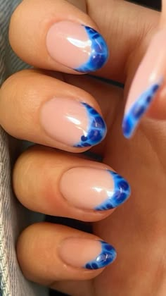 a woman's hand with blue and pink nail polish on it, holding up her nails