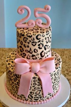 a leopard print birthday cake with pink ribbon and number twenty two on the top tier