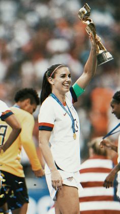 a female soccer player is holding up the trophy