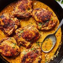 a skillet filled with chicken thighs and garnished with parmesan cheese