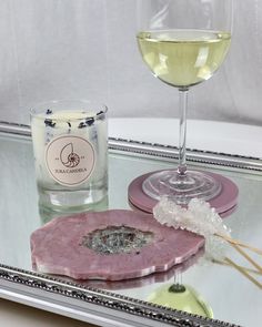 a glass of white wine sitting on top of a table next to a pink object