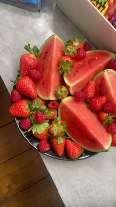 watermelon slices and strawberries are on a plate next to a box of fruit