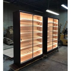 two glass doors are open to show the inside of an empty refrigerator in a warehouse