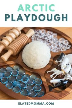 an arctic playdough on a wooden plate with rocks and other items in it