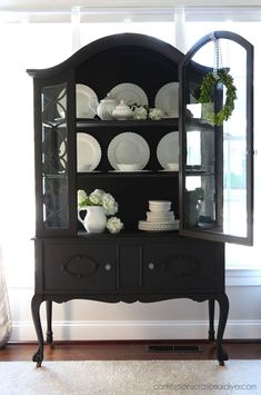 a black china cabinet with plates and flowers on it