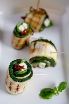 small appetizers with toothpicks and greens on a white plate, ready to be eaten