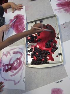 two children are painting on paper with red ink