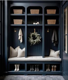 an entryway with blue painted walls and built - in bench, white cushioned pillows, and wreath on the wall