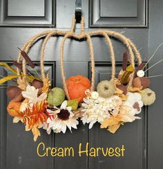 a wreath with flowers and pumpkins hanging on a door