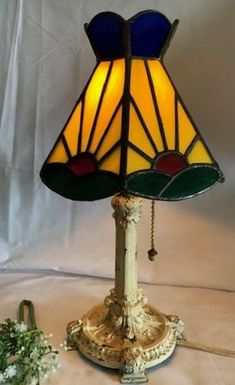 a stained glass lamp sitting on top of a table next to a white cloth covered wall